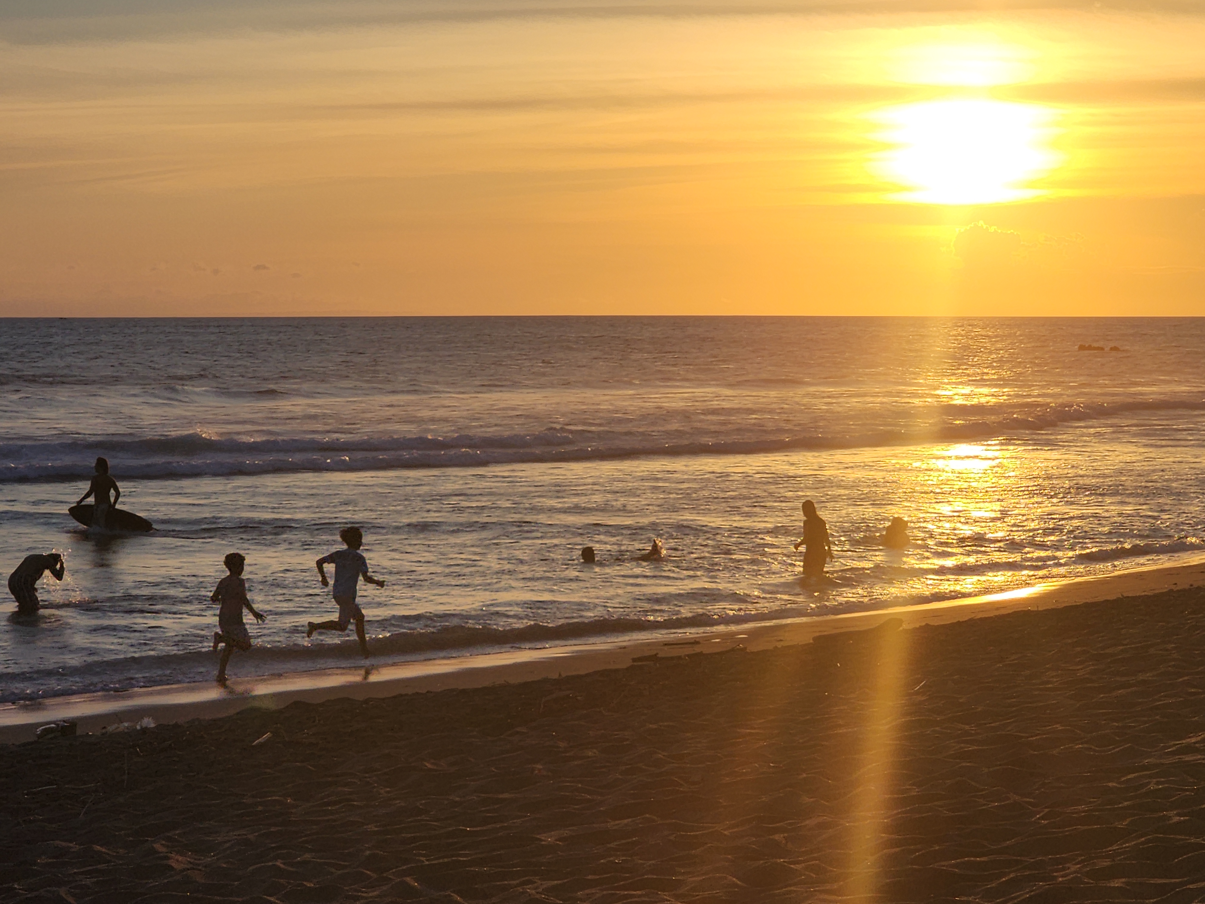 Children playing freely on the beach at golden hour