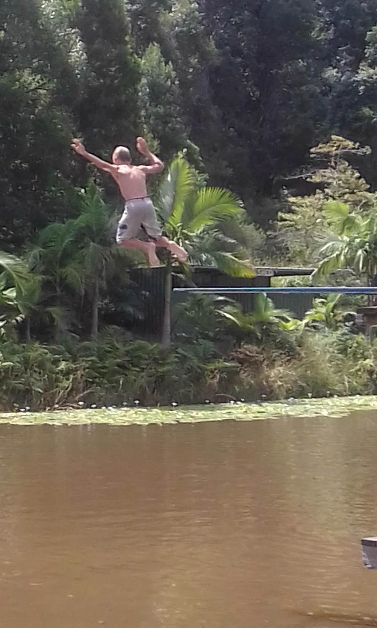 A child mid-air over a dam, arms up, caught between the platform and the water