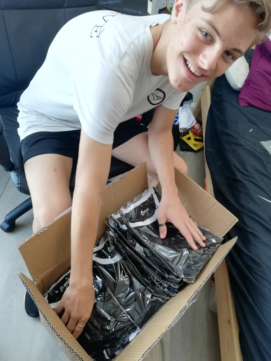Her younger son at fifteen, grinning over a box of his first activewear stock